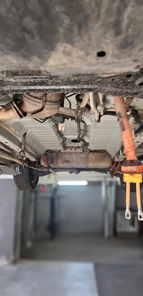 Locașul gol al bateriei sub un Mitsubishi Outlander PHEV, cu cablurile de înaltă tensiune